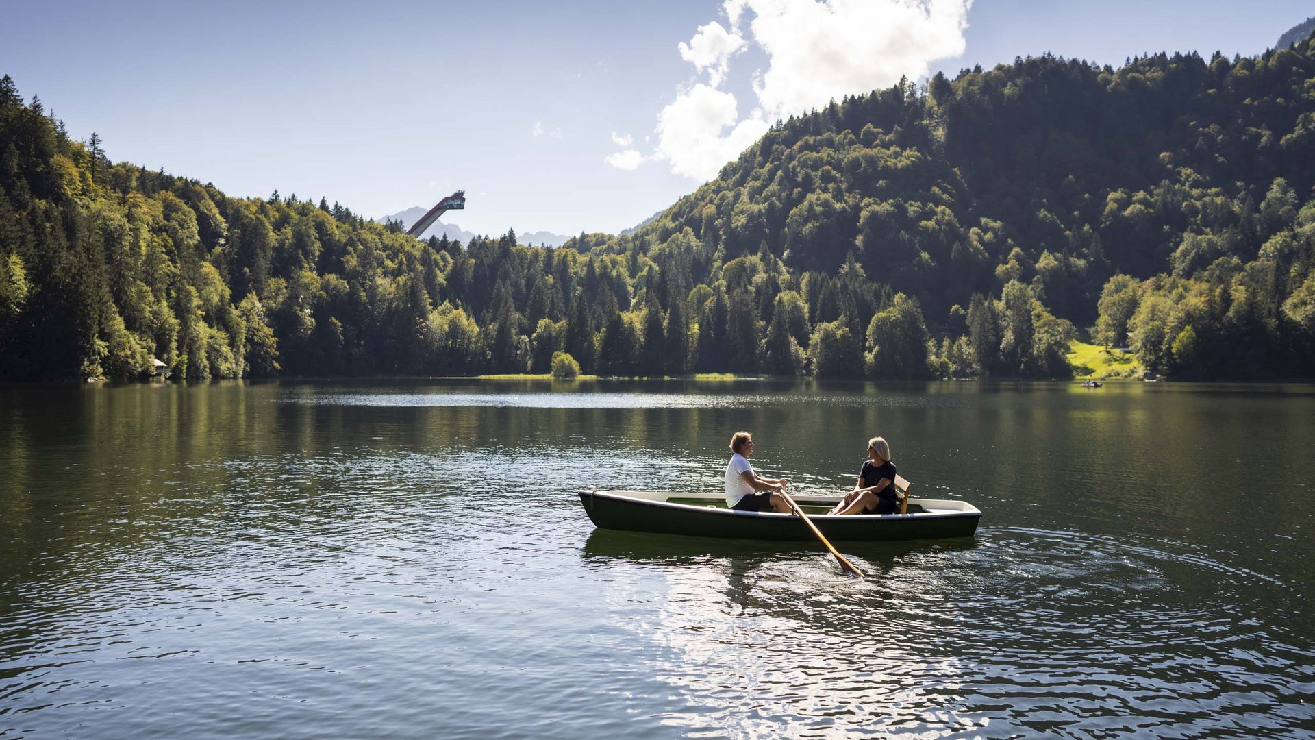 Plan your holiday in Oberstdorf Two people rowing on a lake surrounded by forest and mountains