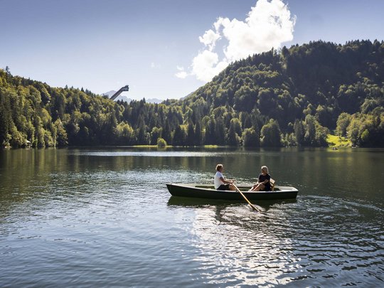 Hahnenköpfle: holiday apartment, lodge & hotel in Oberstdorf Two people rowing on a lake surrounded by forest and mountains