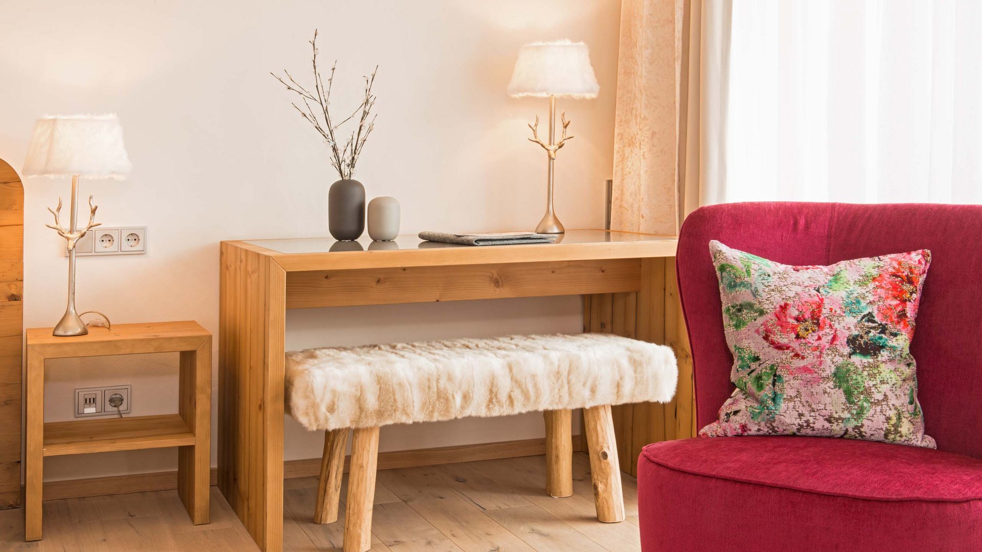 Hotel und Ferienwohnung im Allgäu, Oberstdorf Gemütliches Wohnzimmer mit rotem Sessel, Holztisch und flauschiger Bank