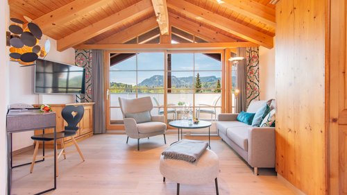 Wählt hier eure Ferienwohnung im Allgäu! Helles Wohnzimmer mit Holzdach und Blick auf Balkon und Berge