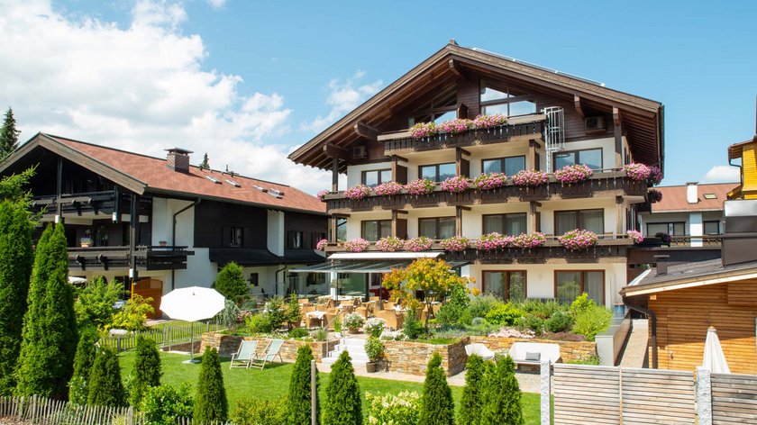 Hotel und Ferienwohnung im Allgäu, Oberstdorf Traditionelles Chalet mit Blumen und Terrasse bei Sonnenschein