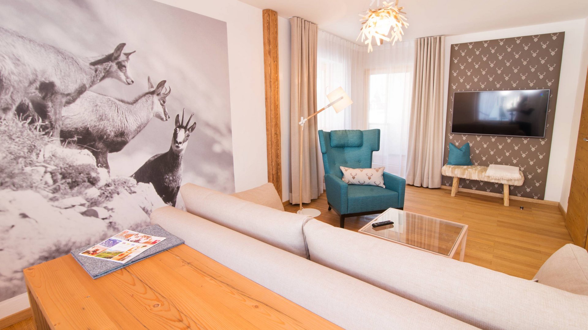 Hotel und Ferienwohnung im Allgäu, Oberstdorf Modernes Wohnzimmer mit Sofa, Sessel und Wandbild von Gämsen