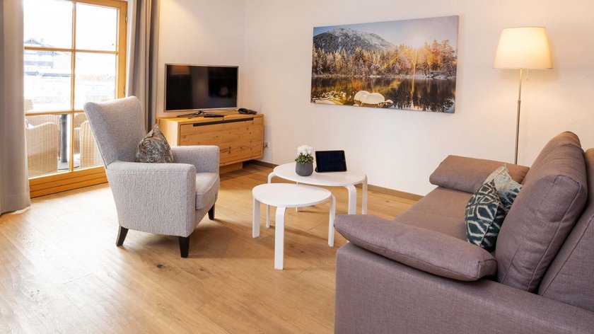 Hotel und Ferienwohnung im Allgäu, Oberstdorf Gemütliches Wohnzimmer mit Sofa, Sessel, TV und einem Bild an der Wand