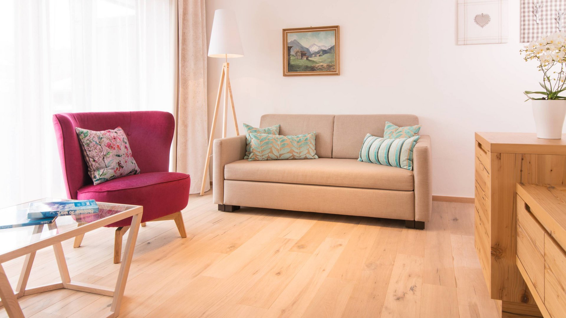 Hotel und Ferienwohnung im Allgäu, Oberstdorf Modernes Wohnzimmer mit rotem Sessel, beigem Sofa und Holzfußboden