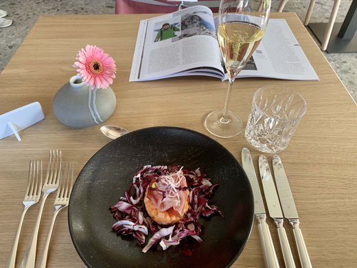 Hotel oder Ferienwohnung in Oberstdorf? Beides! Vorspeise mit rohem Fisch auf schwarzem Teller, Blumendeko und Getränken auf Tisch