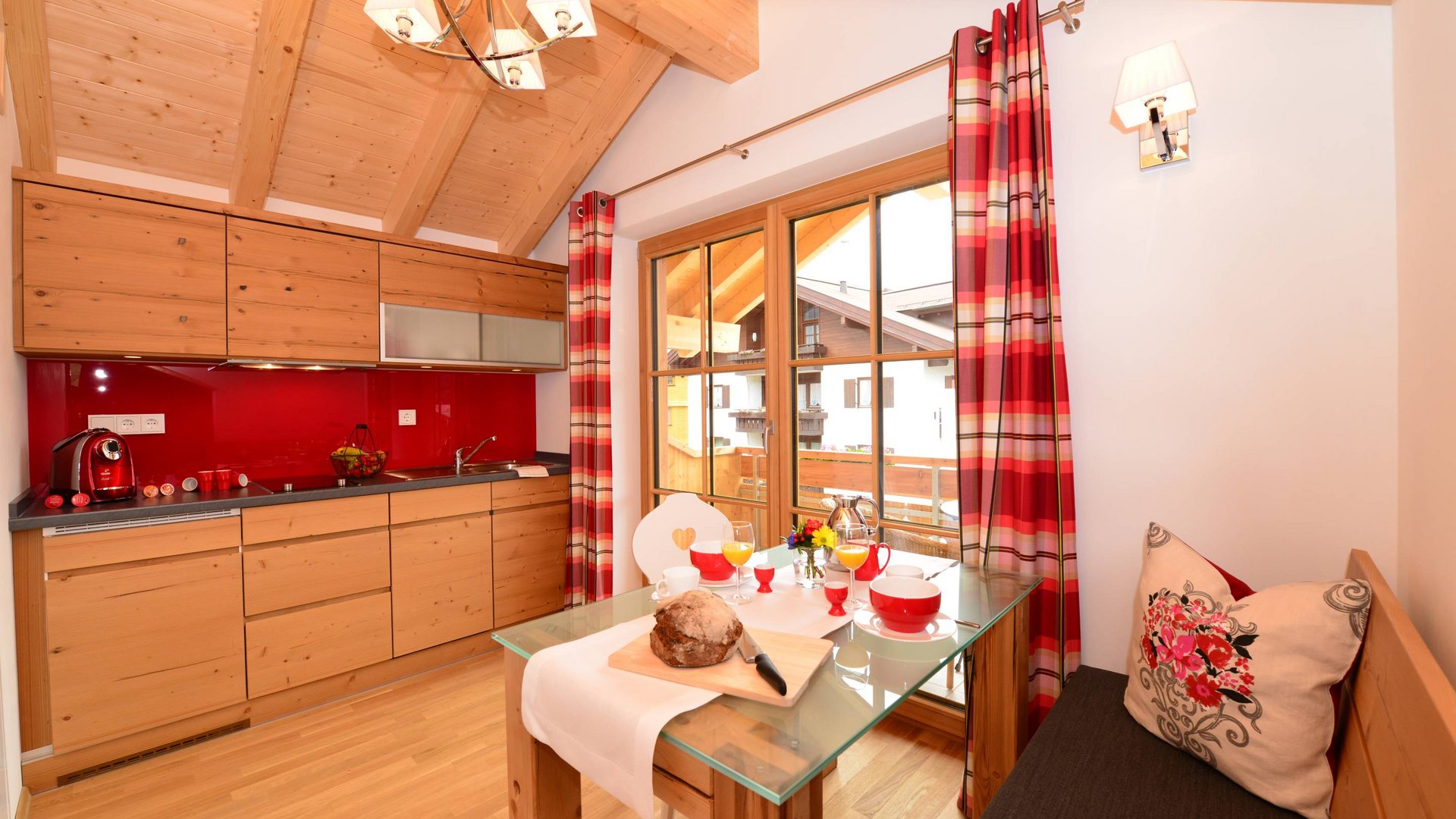 Hotel und Ferienwohnung im Allgäu, Oberstdorf Kleine gemütliche Küchenecke mit Holzschränken und rot karierten Vorhängen.