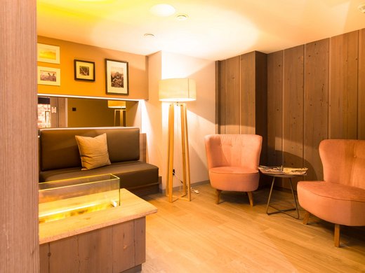 Your wellness hotel in Oberstdorf Cozy seating area with sofa, two armchairs, and floor lamp in a warmly lit room